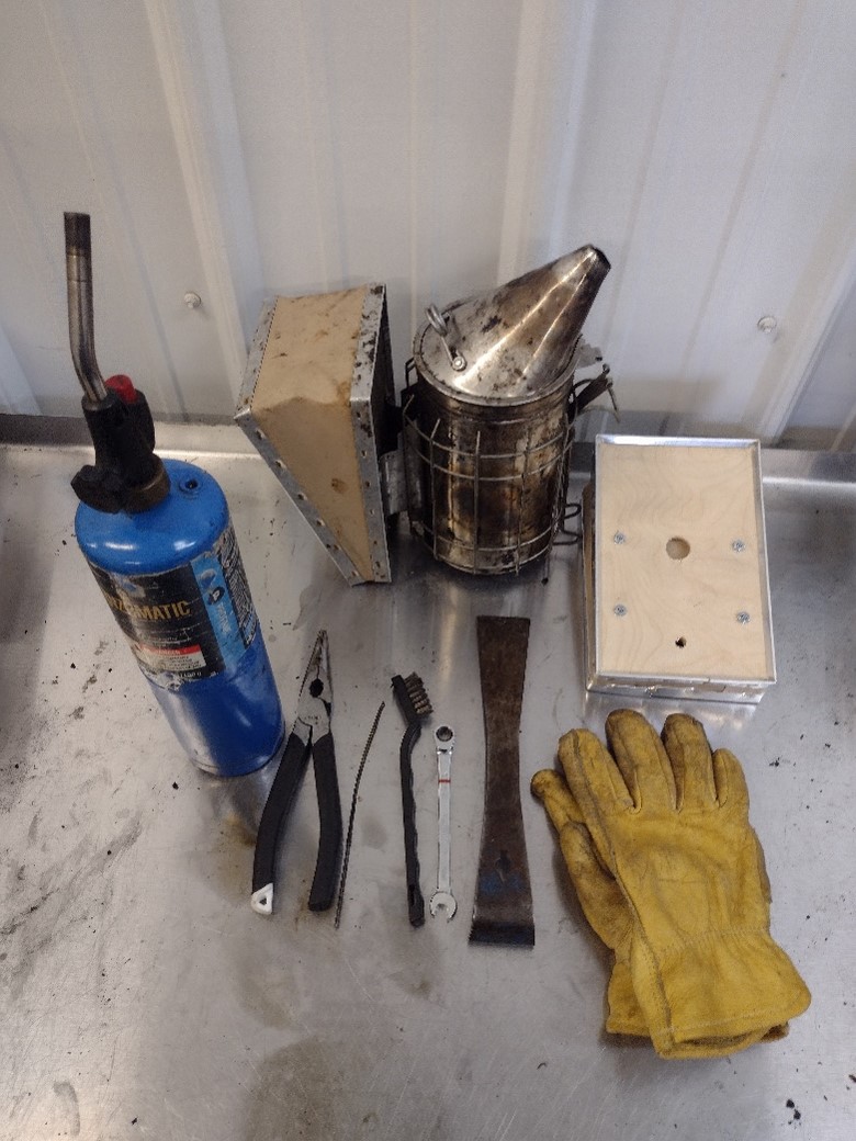 Photo of a torch, pliers, wire brush, wire, wrench, pair of gloves, spare bellow, and smoker